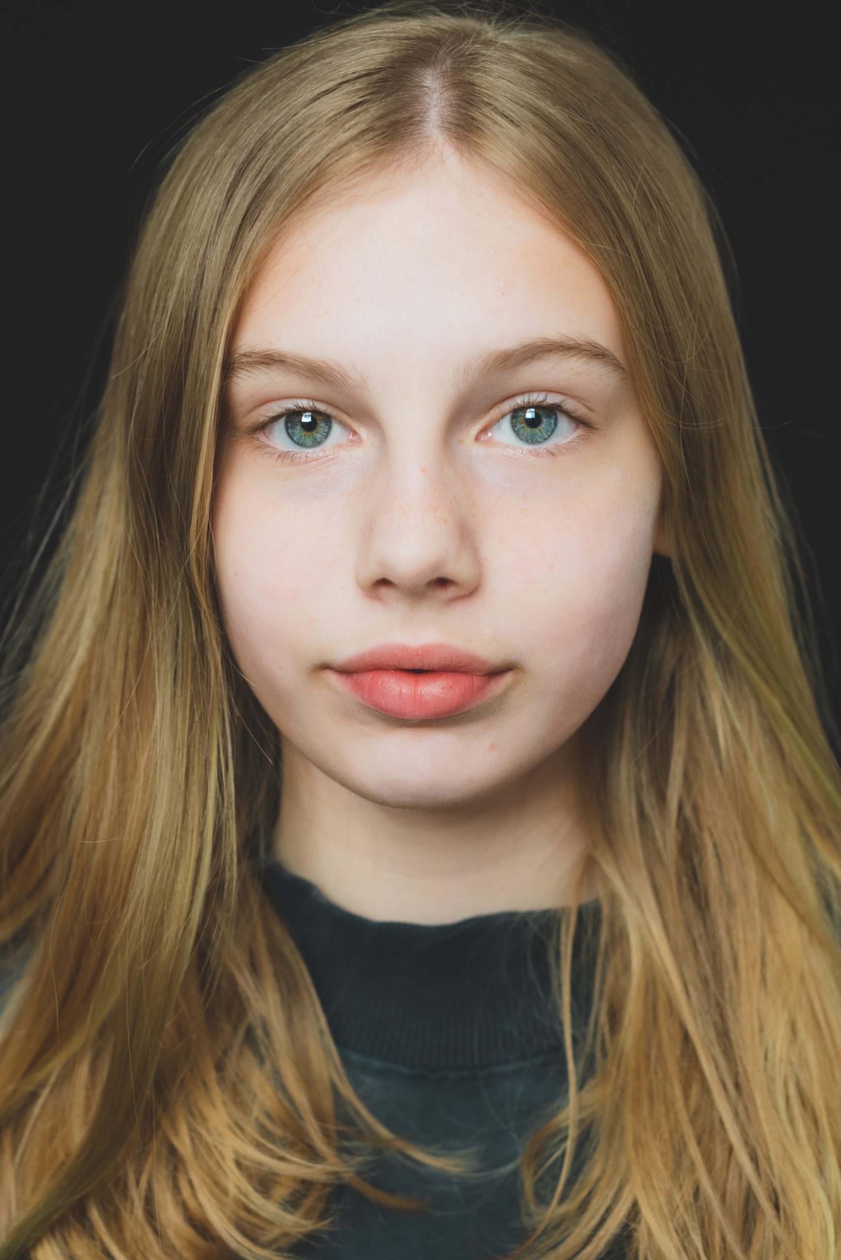 indringend kleurenportretfoto van een   stoere tienerdame met een zwarte  fotoachtergerond