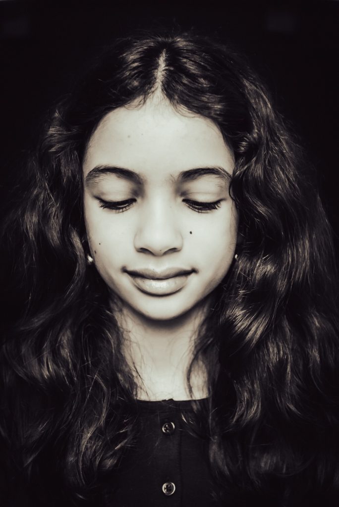 zwart-wit foto van een tienermeisje die sereen kijkt en haar ogen bijna dicht heeft