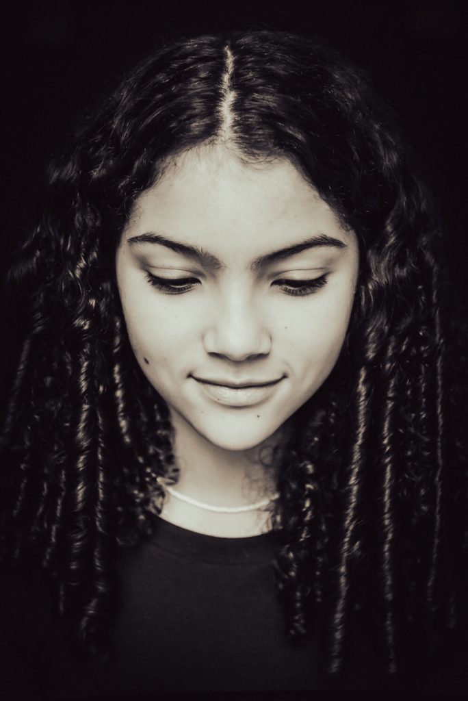 zwart-wit foto van een tienermeisje die sereen kijkt en haar ogen bijna dicht heeft