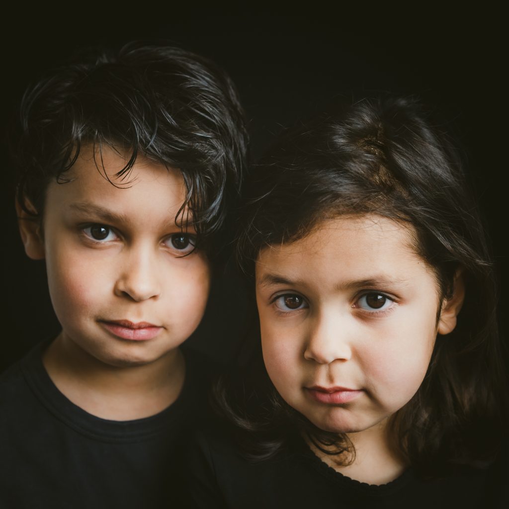 prachtige kleurenportretfoto van 2 kinderen met een zwarte achtergrond en zwarte kleding